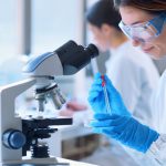 Mujer científica mira a través de un microscopio
