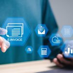 Dedo señalando una factura electrónica al lado de un ordenador portátil