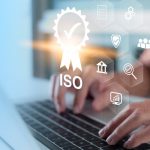 Un científico teclea en su ordenador sobre el que se encuentra un sello de certificación ISO