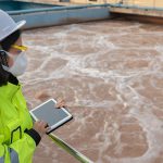 Mujer en una central de tratamiento de aguas realizando un informe