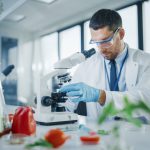 Científico observando alimentos a través de un microscopio